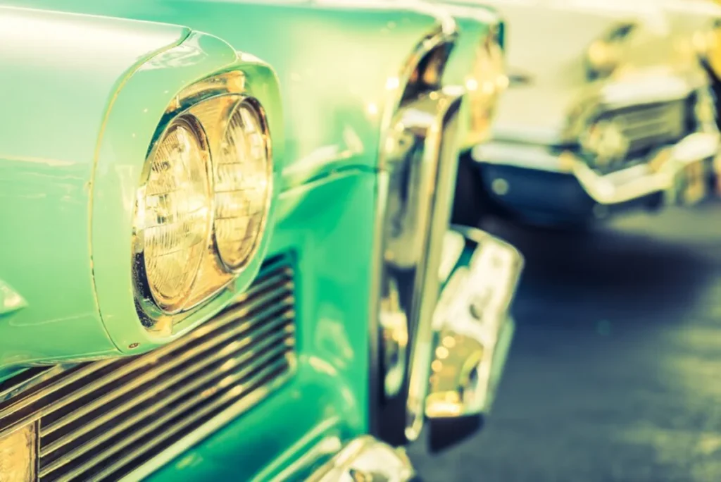 Close-up of the headlight and grille of a vintage mint green car.
