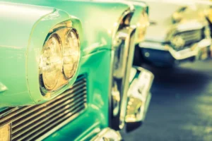 Close-up of the headlight and grille of a vintage mint green car.