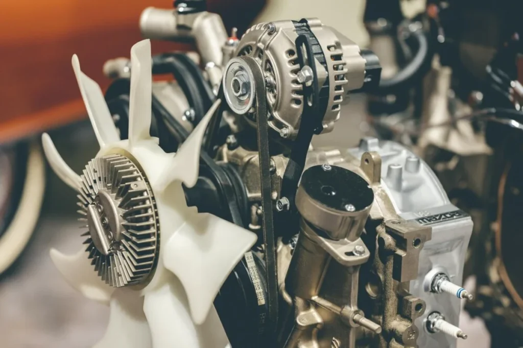 Close-up of a complex car engine showing belts, gears, and cooling fan