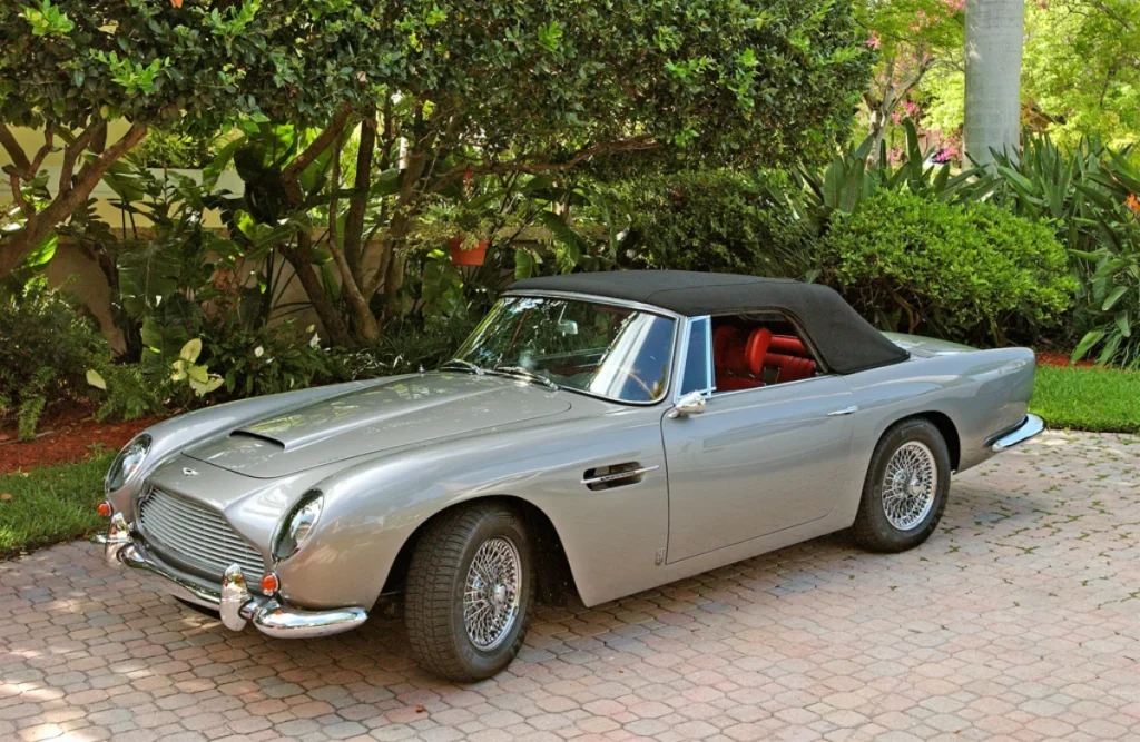A classic silver Aston Martin DB5 convertible with a black soft top