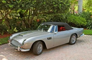 A classic silver Aston Martin DB5 convertible with a black soft top