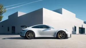 A white Porsche 911 GT3 parked outside a modern white building with clear blue skies