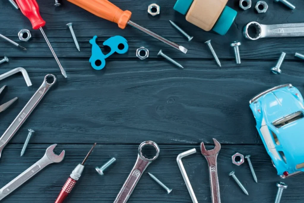 Various tools and hardware items including wrenches, screws, and a toy car are scattered