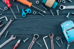 Various tools and hardware items including wrenches, screws, and a toy car are scattered